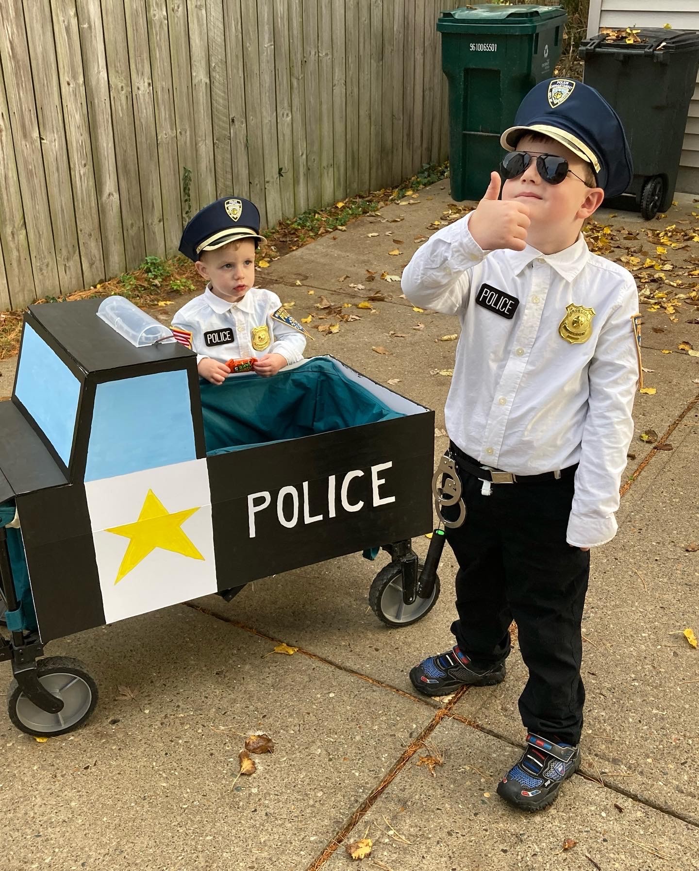 Two children dressed up like officers with child sized police car